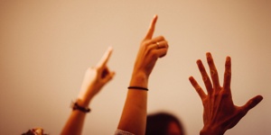 Hände verschiedener Menschen ragen in die Luft, um sich zu melden.